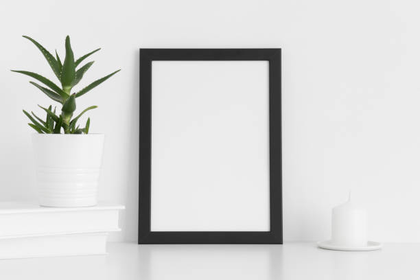 istock Black frame mockup with workspace accessories and a aloe vera on a white table.Portrait orientation. 1267501002