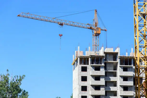 modern apartment building during construction with tower crane on blue sky background
