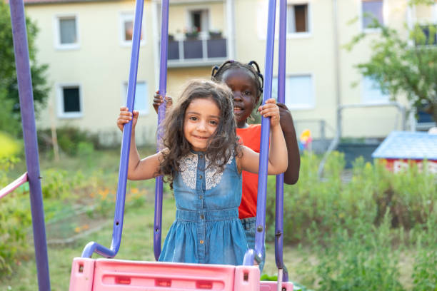 istock summer outdoor fun: two girls on a swing in backyard 1267506421