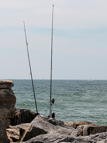 Two fishing poles on the rocks of a jetty on the coast of Fire Island New York,