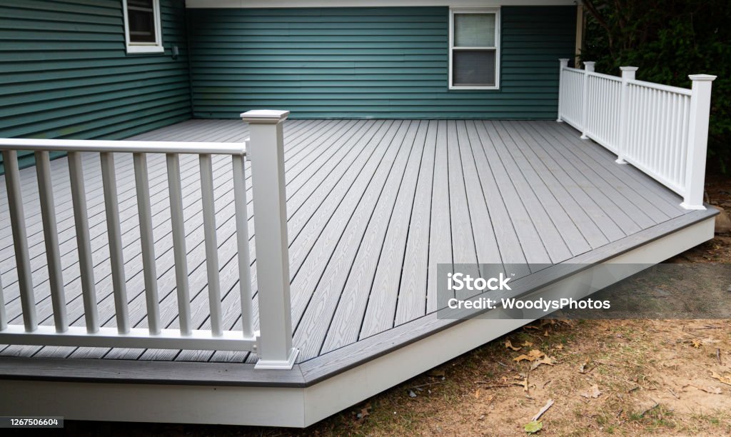 New composite deck New composite deck on the back of a house with green vinyl siding.with whie railings. Deck Stock Photo