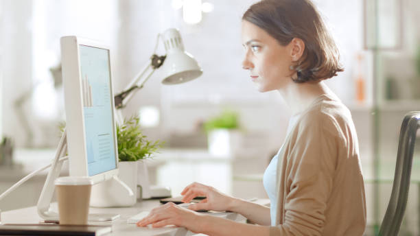 istock Young Beautiful Woman Works at Her Desk Using Personal Computer. She Works in a Bright Modern Lightsome Office Space. 1267507280
