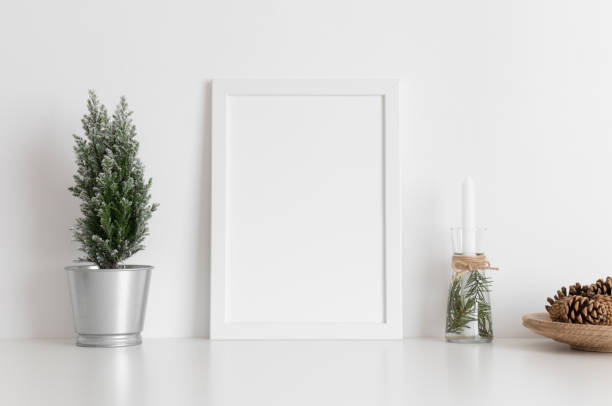 istock White frame mockup with a cypress tree, candles and pine cones on a white table. Christmas decoration. 1267510745