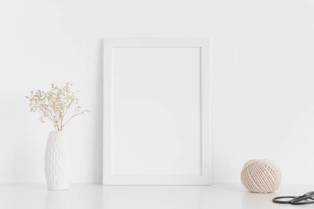 istock White frame mockup with workspace accessories  and gypshophila in a vase on a white table.Portrait orientation. 1267511366