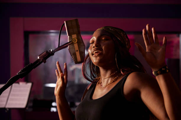 African-american female singer recording vocals on microphone in music studio recording booth African-american female singer recording r&b vocals on microphone in professional music studio recording booth rap stock pictures, royalty-free photos & images