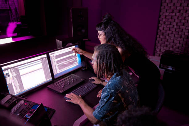 Mixed-race female artist working with african-american music producer on her song in music studio Mixed-race hipster female artist working with african-american male music producer on her song in professional music studio sound mixer photos stock pictures, royalty-free photos & images