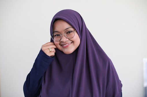Portrait of Muslim female adult trying out 'tudung' (hijab) material.