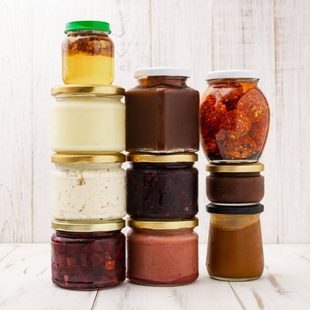 istock Various jars with canned vegetables, oils on a light wooden background. 1267513012