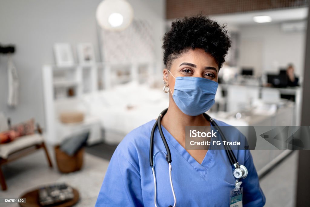 Portrait of a young nurse/doctor on a house call with face mask Protective Face Mask Stock Photo