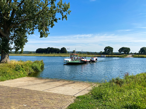 Cuijk, Netherlands - August 19. 2020: View on ferry to Middelaar over river maas in rural landscape in summer (focus on boat)