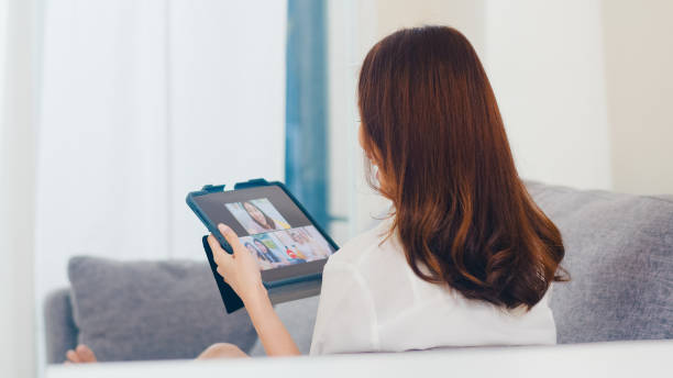 young asian business female using tablet video call talking with family while working from home at living room. - father digital tablet asian ethnicity daughter imagens e fotografias de stock