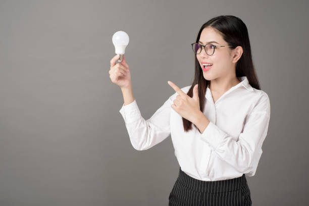 istock Beautiful intelligent woman is holding light bulb in studio 1267527388