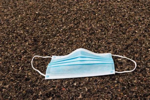 istock Used medical protective mask thrown on the floor. 1267528574