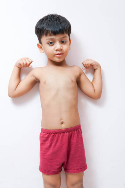 赤い下着を着て、白い背景に対して上腕二頭筋を示すシャツレスの小さな男の子。 - flexing muscles child little boys bicep ストックフォトと画像