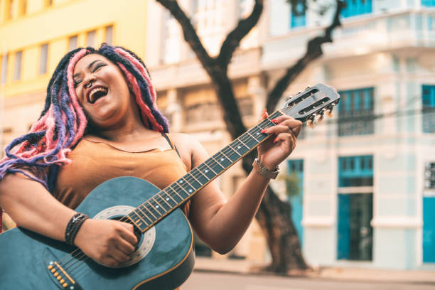 アコースティックギターを弾くラスタファリアン女性 - street musician ストックフォトと画像