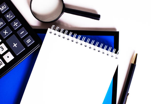 istock Notebook, pen, calculator and magnifier lie on a white and blue background. 1267544852