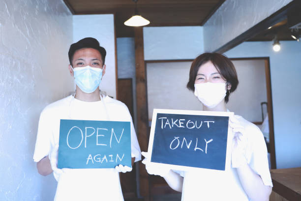 istock Happy owner holding the signboard at a cafe wearing a facemask 1267544932