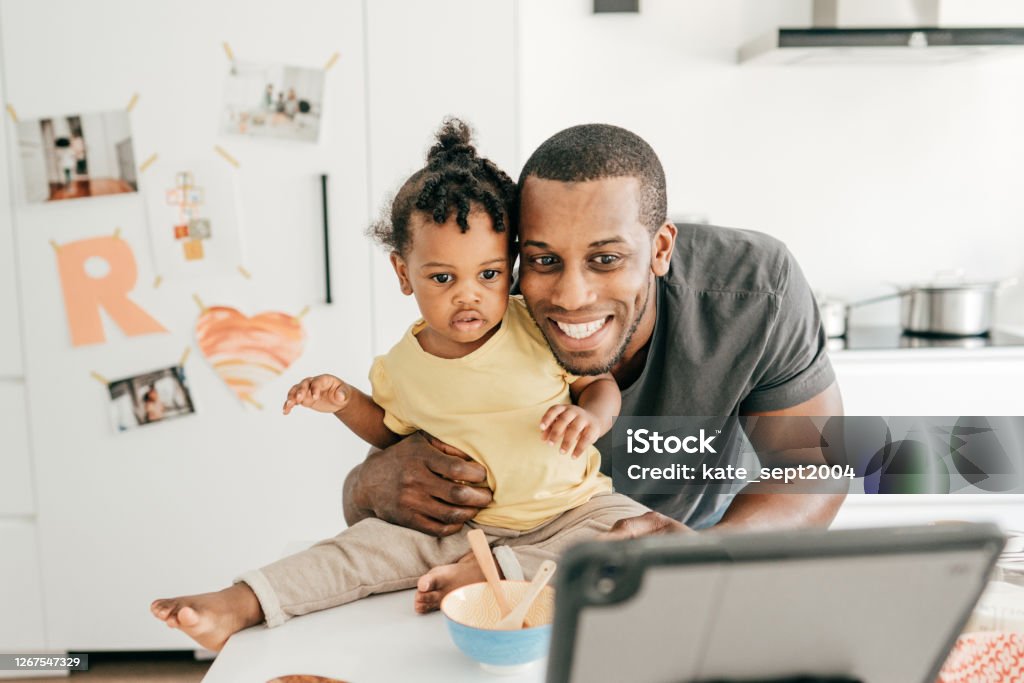 Calling to grandmother Dad and baby daughter in the kitchen using tablet Care Stock Photo
