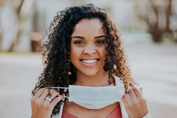 Woman removing face protection mask and smiling