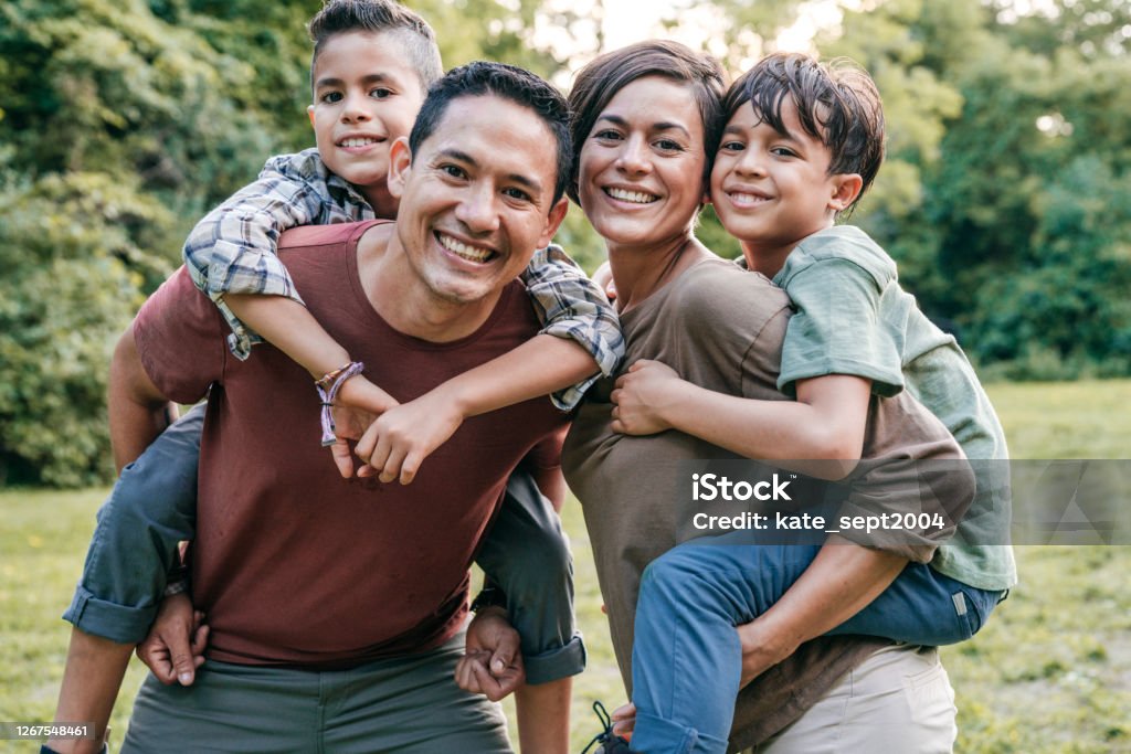 Investing in children education Family outdoor with two elementary age kids. Waist up portrait of the family looking at camera Family Stock Photo