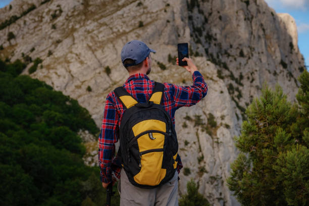 istock Strong man hiker taking photo with smart phone at mountain peak. 1267550470