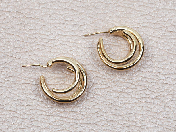 istock Gold women`s earrings on beige leather background 1267560266