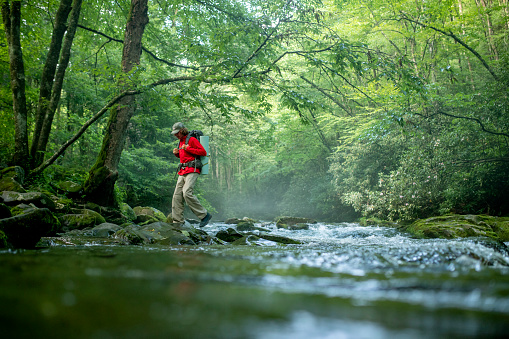 Backpacker hiking across a river in the great smoky mountains national park.