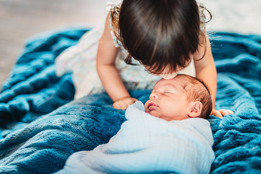 Newborn baby boy and toddler sister get to know each other at home