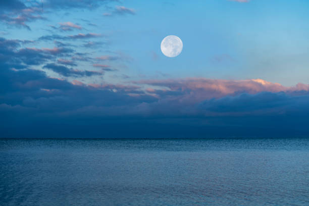 istock Beautiful sunrise on the lake with full moon. 1267561316