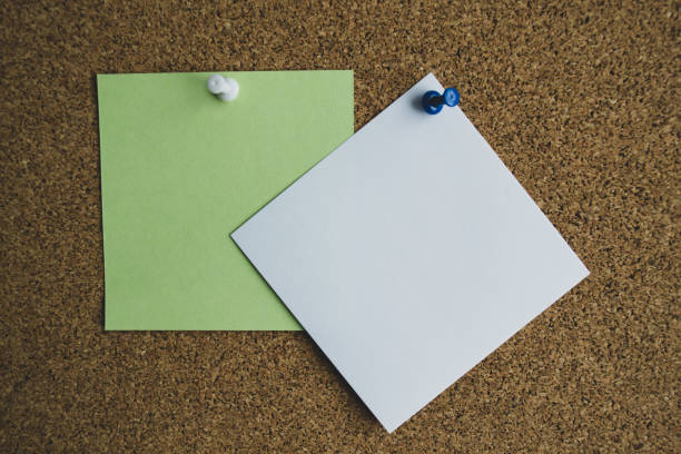 istock Three paper notes green, white and yellow color on a cork Board, attached with a white pushpin. Copy space 1267565280