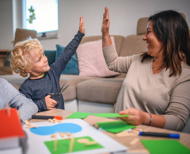 istock Mother and Son Giving High Five While Making Paper Model at Home 1267573503