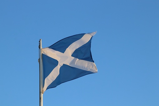 Scottish flag blowing in wind against blue sky
