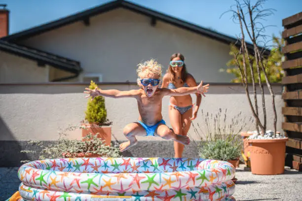 Photo of Cute Caucasian Brother and Sister Having Fun in Inflatable Swimming Pool at Home