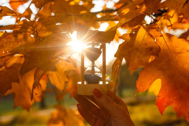 istock Autumn time theme, Sandglass on fallen leaves in various colors with copy space. 1267575761