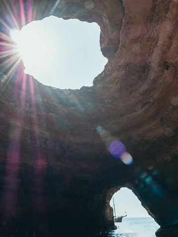 View from inside sea cave in Portugal, sunbeam passing through hole illuminating rocks