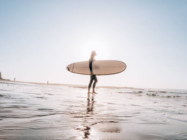 istock Woman with surfboard on beach watching waves in the morning 1267575862