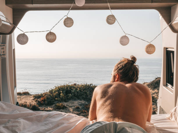 istock Man lying at the back of a van looking at ocean 1267576055