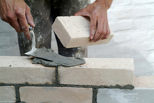 Construction worker laying bricks in a construction site.