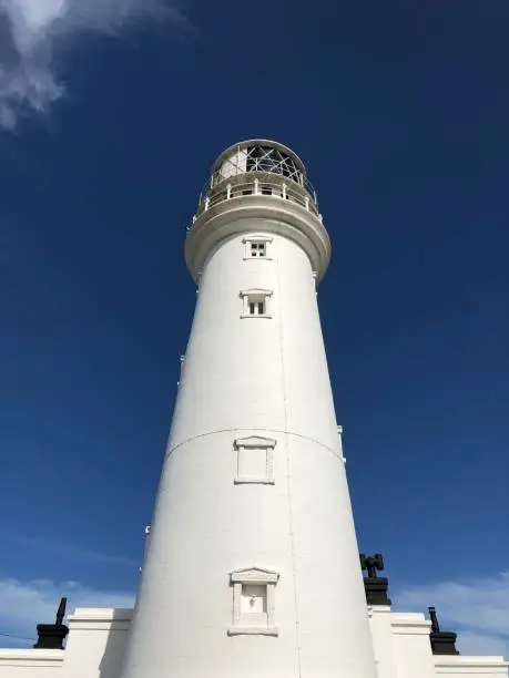 Close up view of the Lighthouse from directly below against a deep blue skyline and bright white cloud