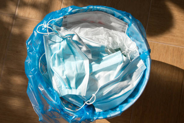 istock Medical masks in the trash bin close up. 1267582265