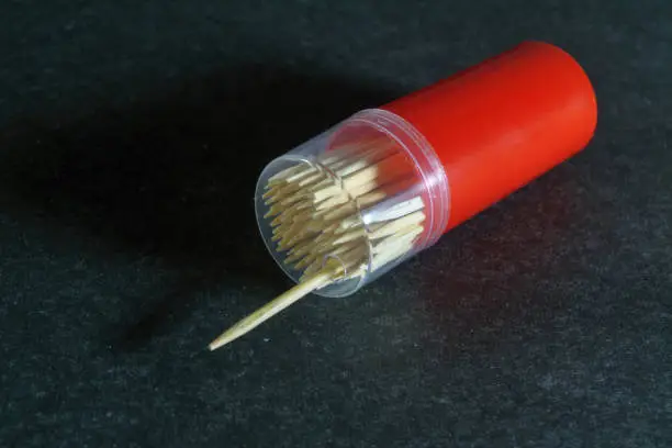 Photo of Case with wooden toothpicks on a dark gray background close-up.