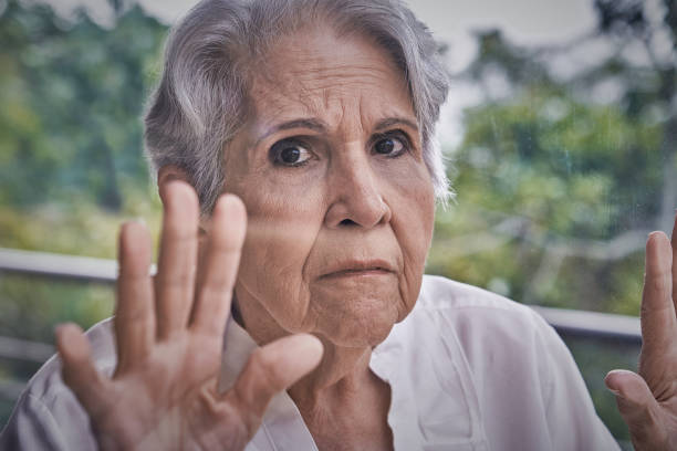 istock Lockdown despair Hispanic senior woman looking through window 1267586670