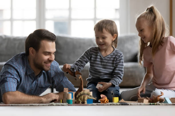 istock Smiling young daddy playing toys with small children. 1267591945