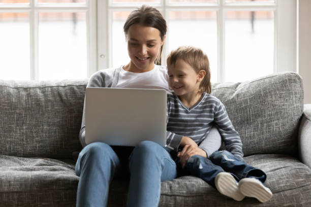 istock Smiling affectionate mum enjoying watching funny cartoons with small son. 1267591971