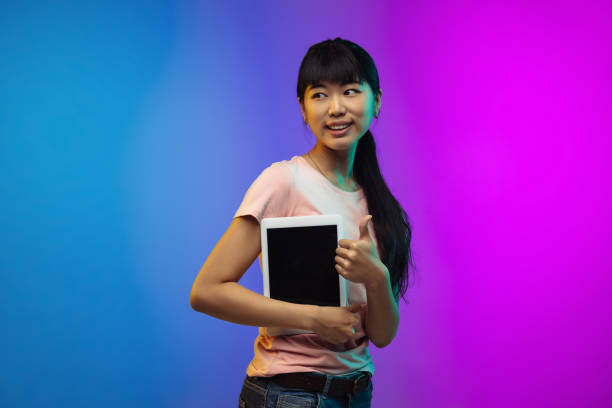 istock Asian young woman's portrait on gradient studio background in neon 1267595329