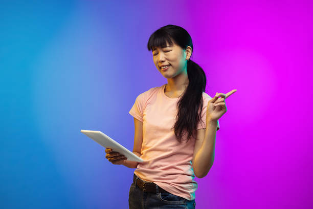 istock Asian young woman's portrait on gradient studio background in neon 1267595332