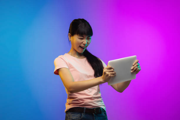 istock Asian young woman's portrait on gradient studio background in neon 1267595336