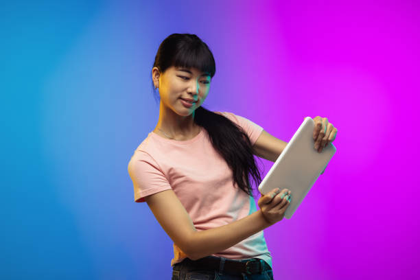 istock Asian young woman's portrait on gradient studio background in neon 1267595338