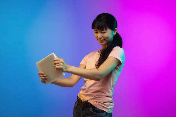 istock Asian young woman's portrait on gradient studio background in neon 1267595339