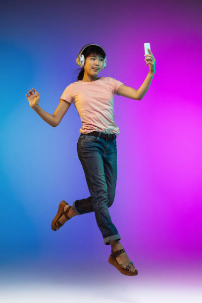 istock Asian young woman's portrait on gradient studio background in neon 1267595357
